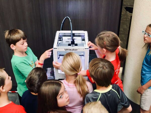 Group of children gathered around a 3D printer