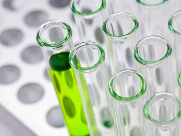 Rack of glass test tubes, one holding bright green liquid