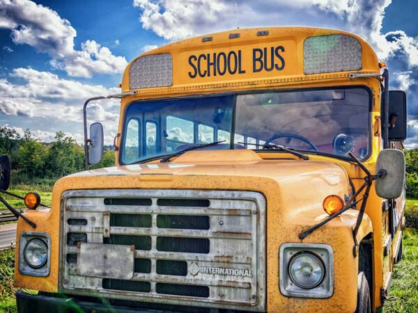 Front of a yellow school bus under a cloudy sky