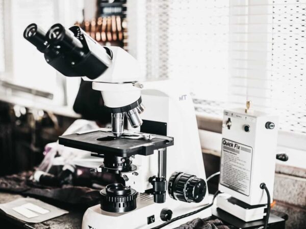 Microscope on a lab bench | Science Safety Black-and-white photo of a laboratory microscope and equipment on a bench