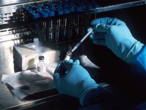 Gloved hands using a pipette in a laboratory