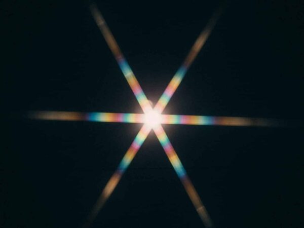 Star-shaped light flare with rainbow colours on a black background