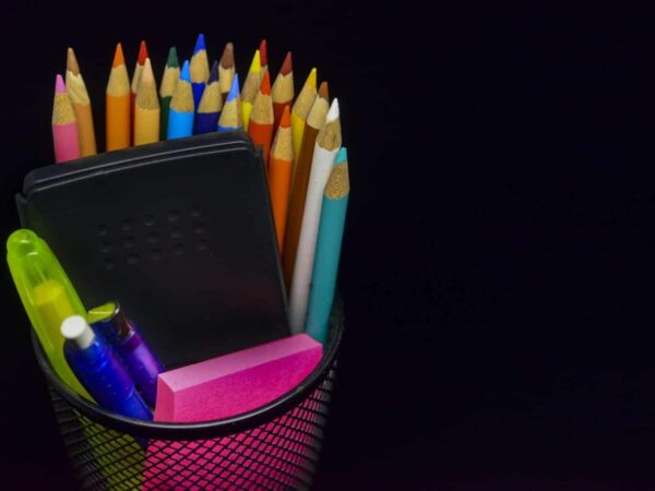 Cup of coloured pencils and markers against a black background