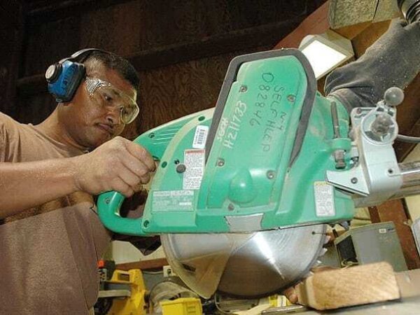 Worker using a radial arm saw | Science Safety Worker in ear defenders and safety glasses using a radial arm saw