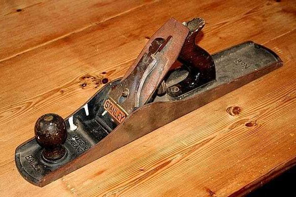 Old metal hand plane resting on a wooden board