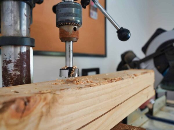 Drill press drilling wood | Science Safety Drill press boring a hole into a wooden board