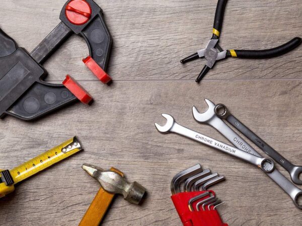 Hand tools on a workbench | Science Safety Hand tools on a wooden surface: clamp, pliers, wrenches, hammer, tape measure and hex keys