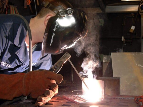 Sailor in a welding helmet welding a metal joint