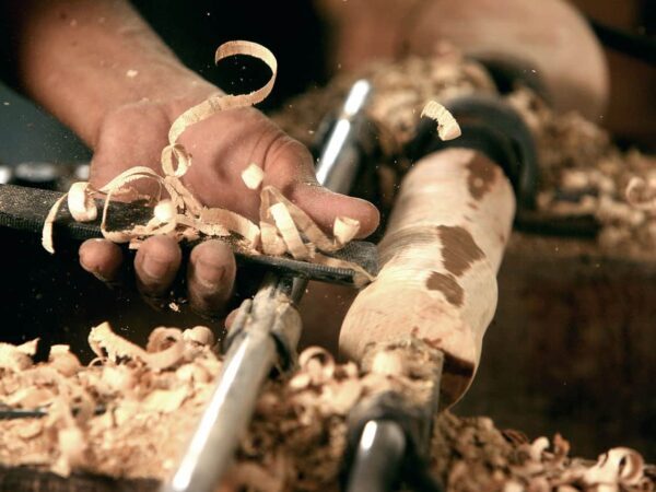 Woodturning in Indonesia | Science Safety Hands turning wood with a chisel, surrounded by wood shavings