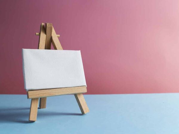 Blank canvas on an easel | Science Safety Small blank canvas on a wooden easel against a pink wall