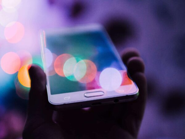 Hand holding a smartphone among colourful blurred lights