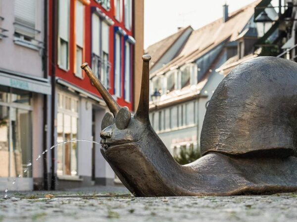 Bronze snail sculpture on a street lined with colourful buildings