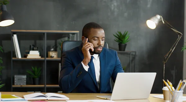 Man on the phone at a desk with a laptop