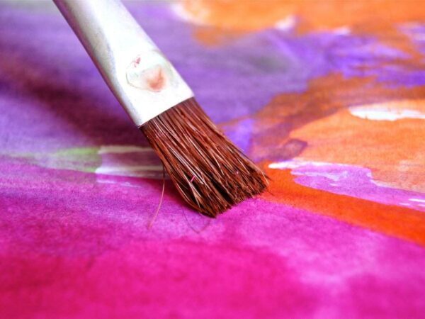 Paintbrush spreading pink and purple paint