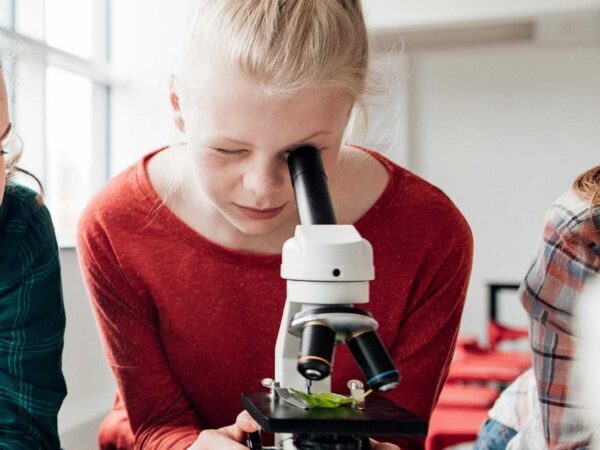 Girl looking into a microscope in a classroom