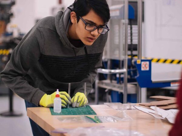 Student working in a makerspace | Science Safety Student in glasses working carefully on a small project at a workshop table