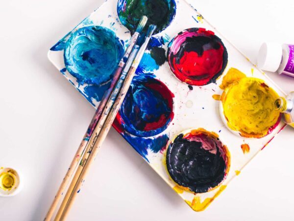 Paint palette with blue, red, yellow and black paint and brushes