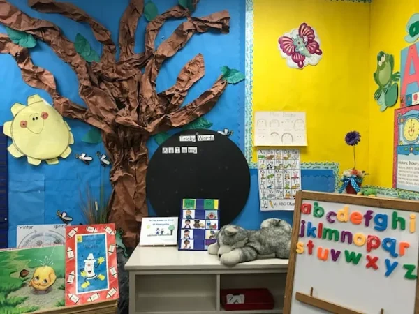 Colourful elementary classroom corner with a paper tree, an alphabet chart and soft toys