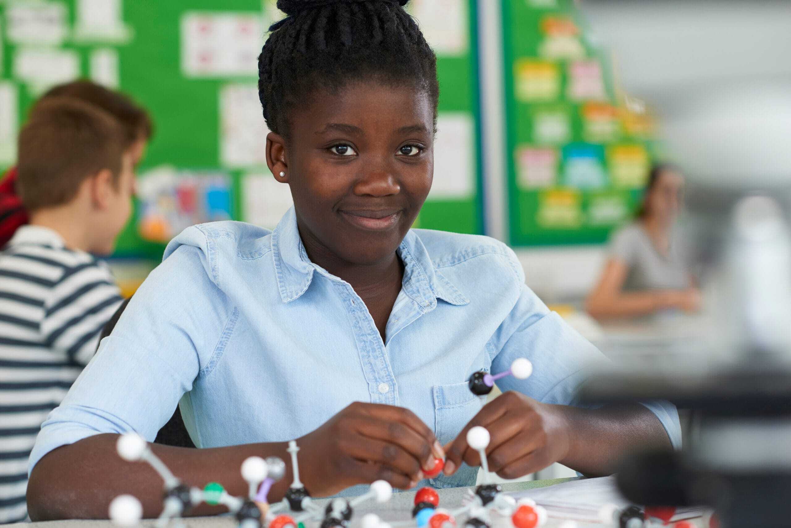 Student at a classroom desk building a molecular model kit
