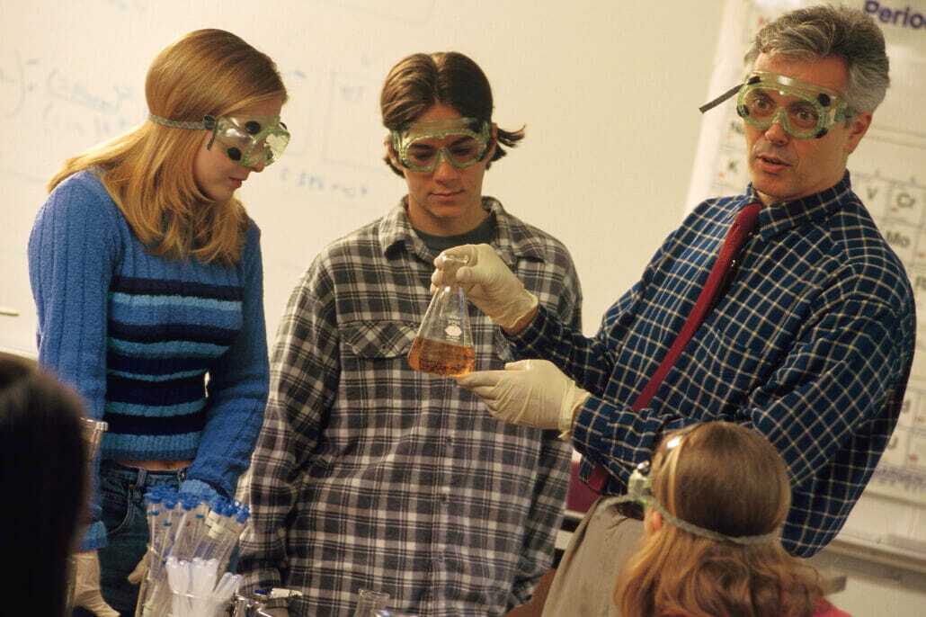 Professor and students in lab class | Science Safety | Science Safety A teacher and students in safety goggles working together in a science lab