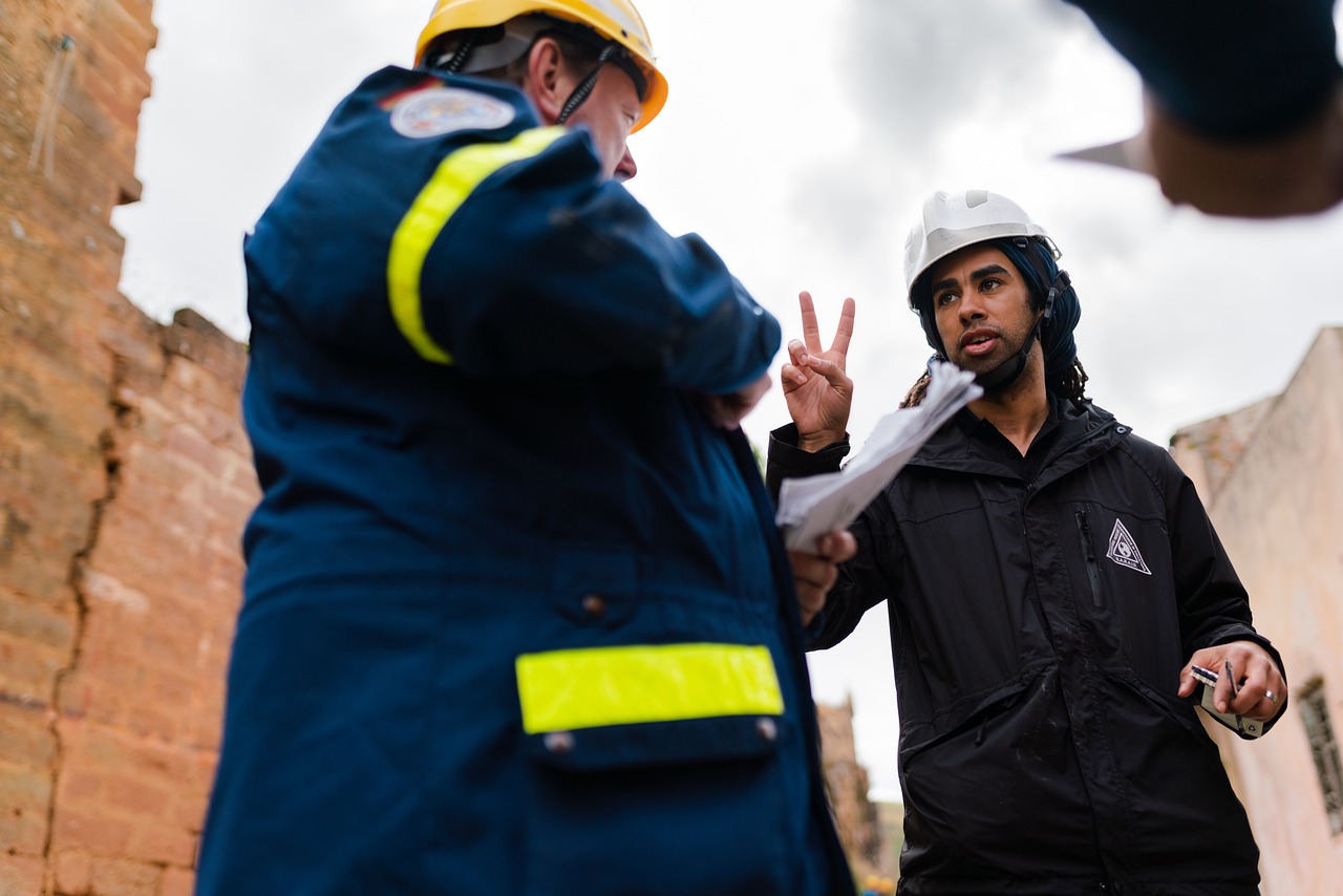 Safety supervisor in a hard hat and reflective coveralls talking with a worker on site